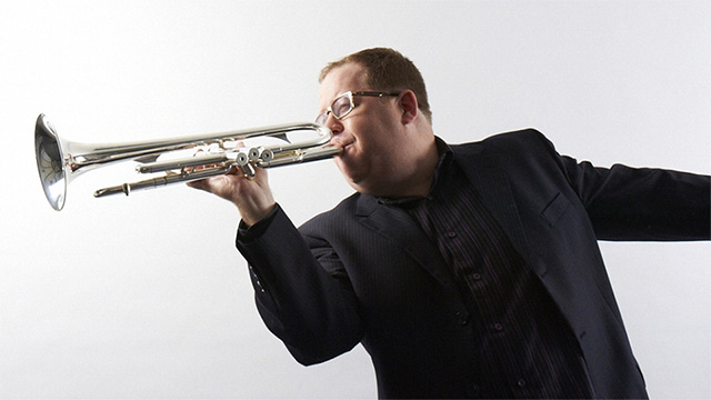 Trent Austin playing a trumpet.