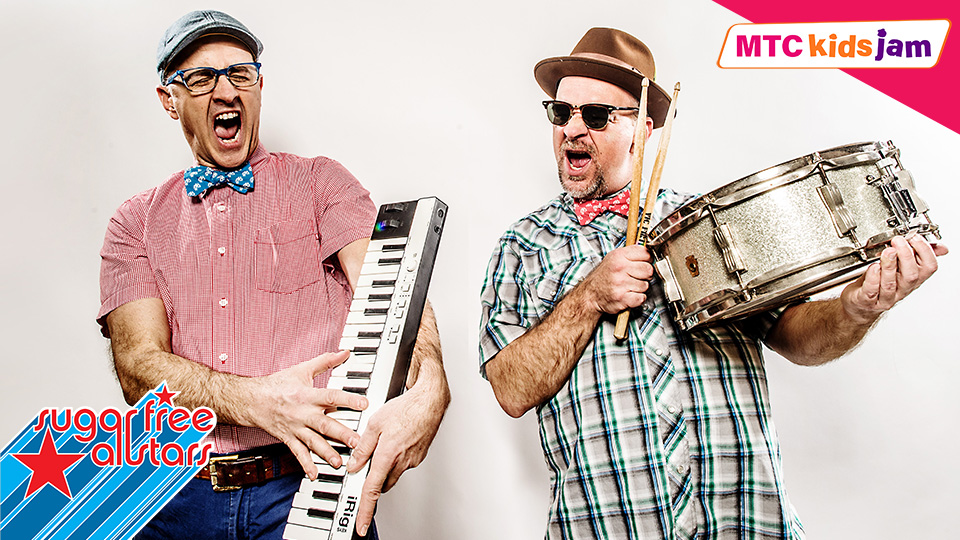 the two members of Sugar Free Allstars - the man on the left is holding a keyboard and smiling and the man on the right is holding up a drum and drum stick