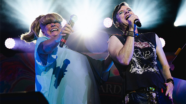 two people singing on stage with a bright light in the background