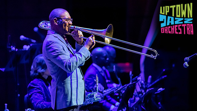 a man playing a trombone on stage with the words Uptown Jazz Orchestra