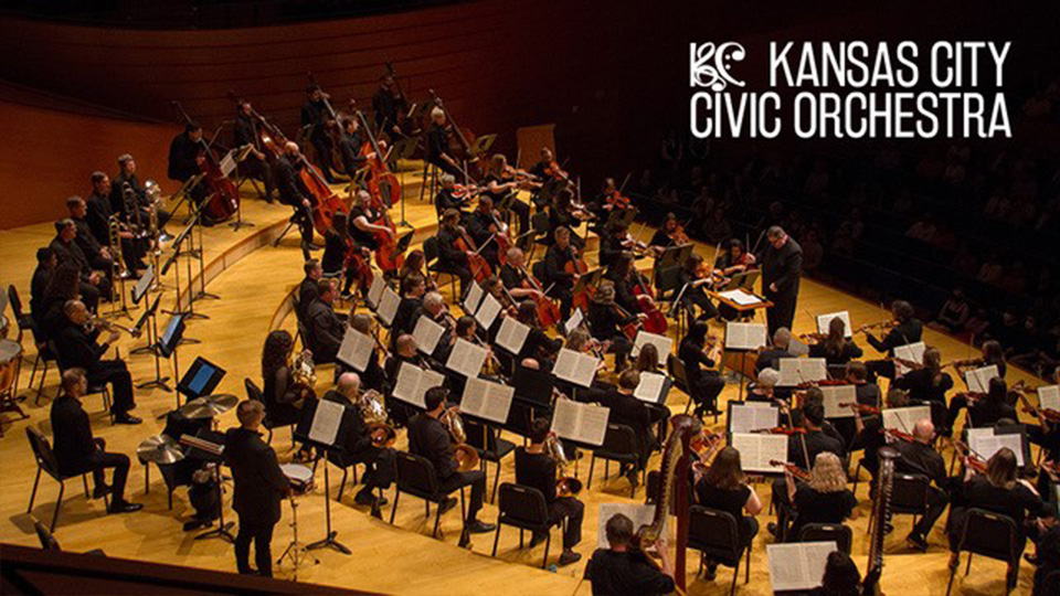 The Kansas City Civic Orchestra performing on stage against a black background