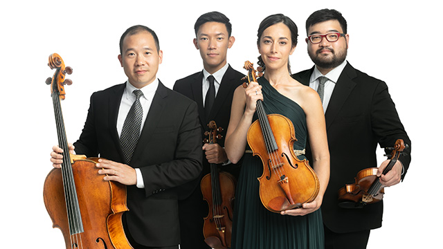 The 4 members of the Parker Quartet pose smiling at the camera while holding up their instruments