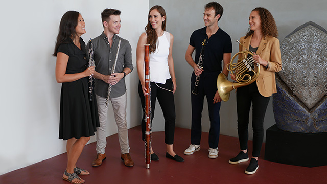 five members of windsync stand together while holding their instruments