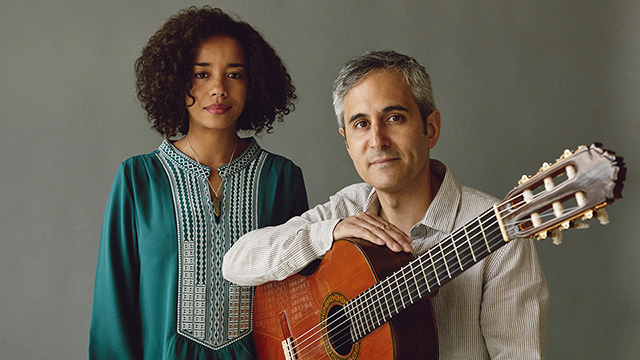 Lamiae Naki stands next to a man holding a guitar