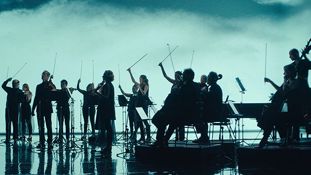 a silhouette of the Australian chamber orchestra on stage against a backdrop of fog