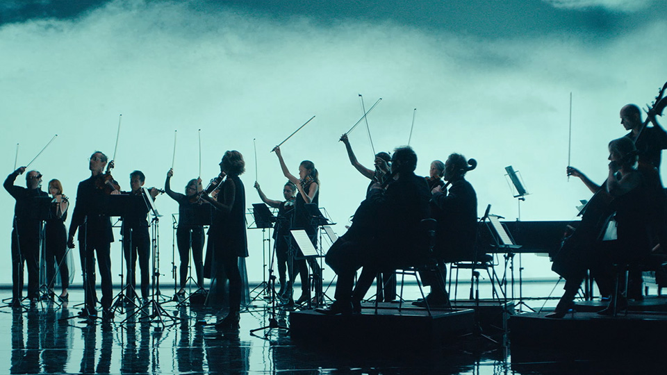 a silhouette of the Australian chamber orchestra on stage against a backdrop of fog