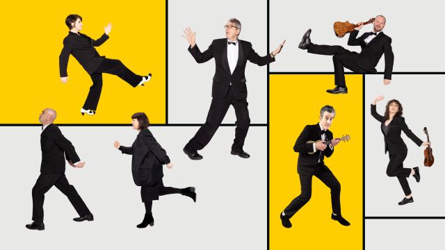 seven musicians in black suits lean on each other in a line