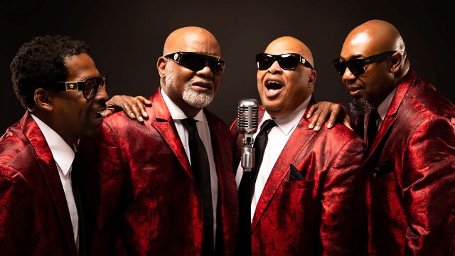 four singers in red suits and sunglasses