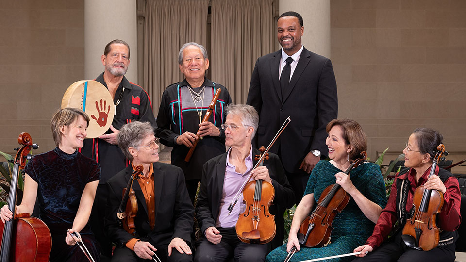 8 musicians holding their instruments and smiling