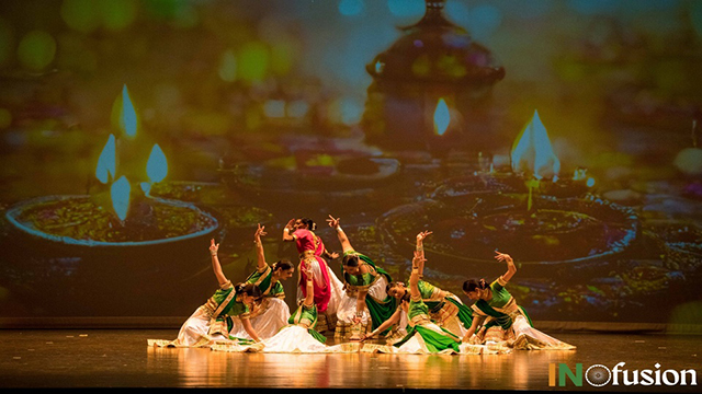dancers on stage in front of a backdrop showing candles and flames, with the logo for INfusion