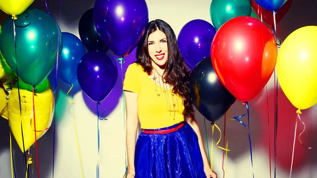 Joanie Leeds standing among a bunch of helium balloons.