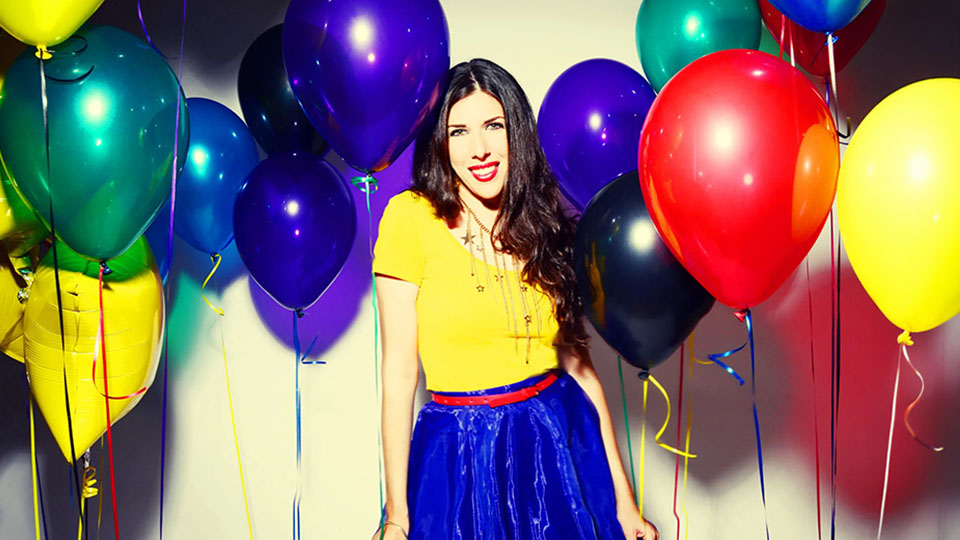 Joanie Leeds standing among a bunch of helium balloons.