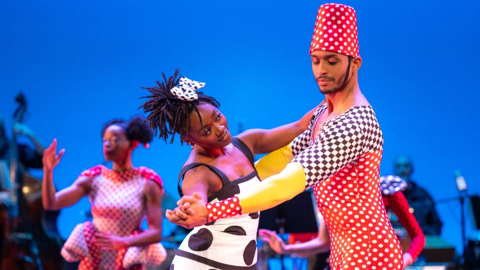 three dancers on stage in colorful costumes
