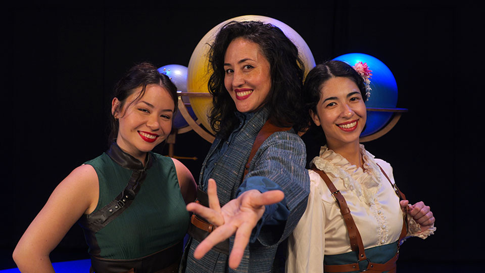 three smiling women pose for a picture in front of a moon background