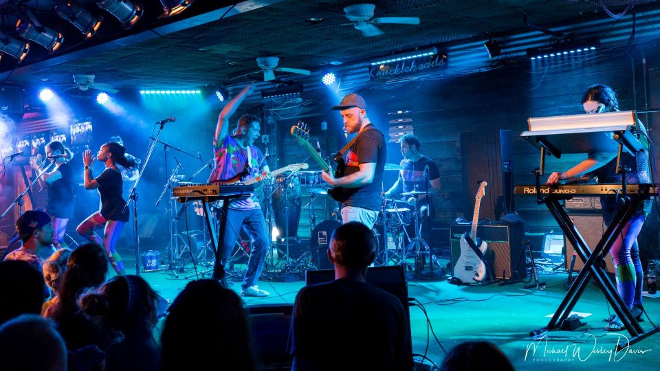 The members of Found a Job performing on a dark stage lit dramatically by bluish lights