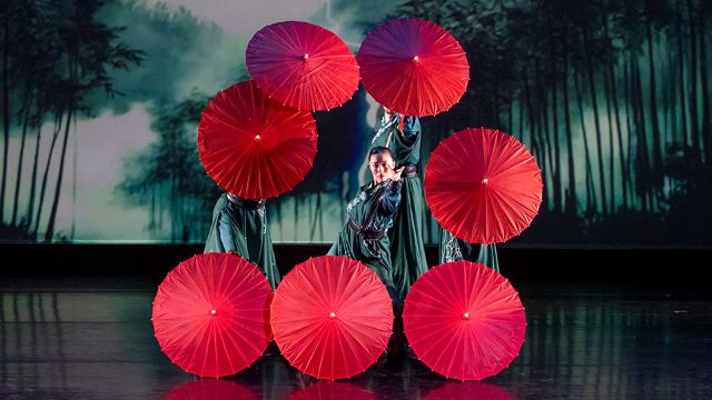 a dancer on stage surrounded by open umbrellas