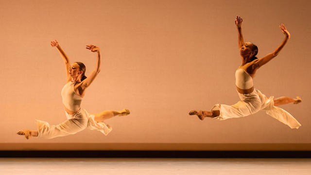 two dancers performing the same jump