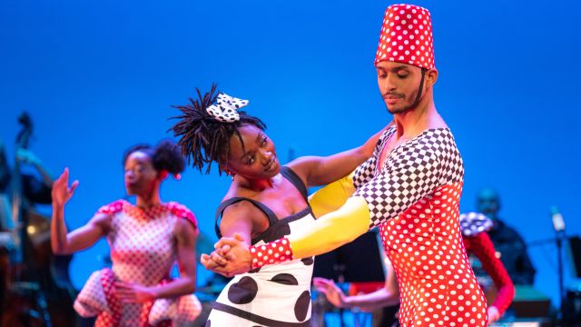 three dancers on stage in colorful costumes