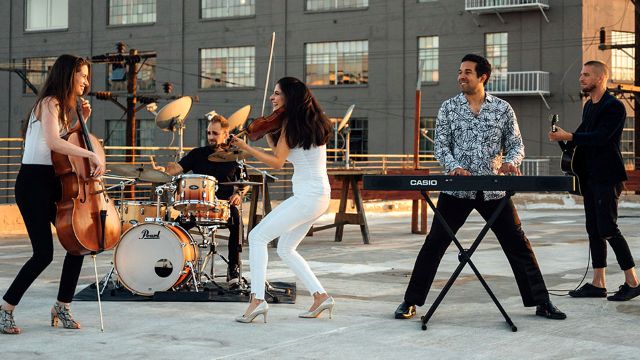 The members of Take3 performing outside in a city