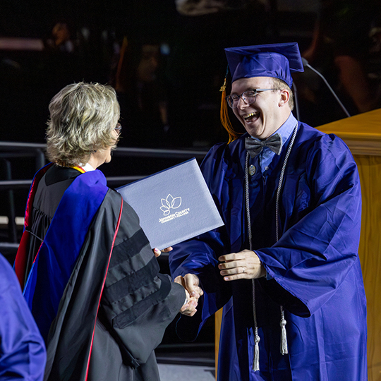 Graduate receiving diploma from college interim president