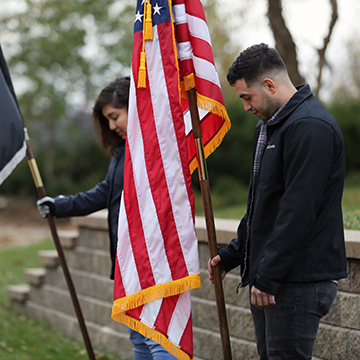 Veterans holding the American flag, heads bowed, as they listen to Taps