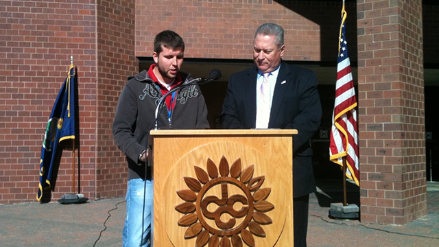 Volunteers standing at a podium outside COMS reading a list of names of fallen service members