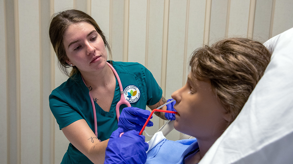 a nursing student works with a simulation dummy