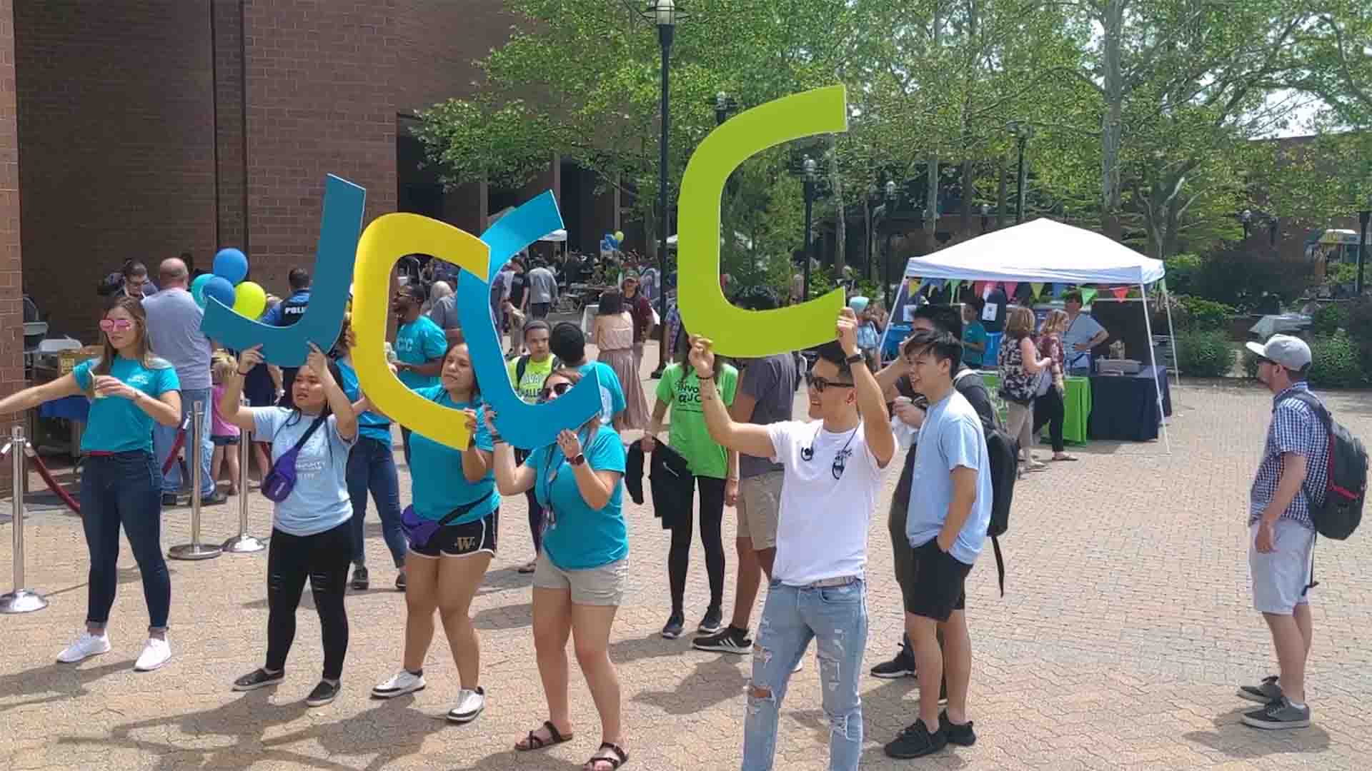 Students in the COMS courtyard during Cav Craze,. They are holding large cardboard letters - J C C C