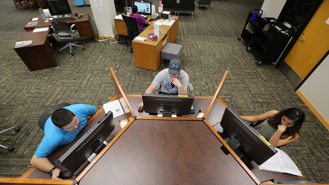 Aerial view of students working at an octagonal computer station in the library