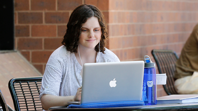 Student seated an outside table working on her laptop